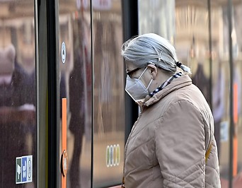 Eine Frau mit FFP2-Maske vor einer Straßenbahn in Wien