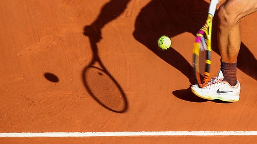 Shadow of a tennis player on a clay court