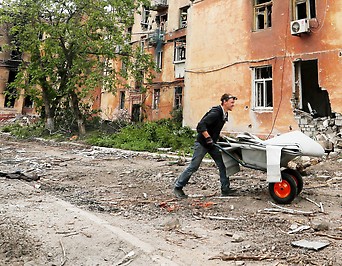 Mann vor zerstörten Gebäuden in Mariupol