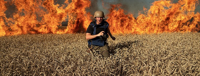 Ein Fotograf flüchtet vor einem Feuer in einem Getreidefeld nahe Kharkiv