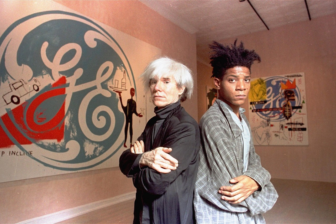 Pop artists Andy Warhol and Jean-Michel Basquiat stehen Rücken an Rücken vor ihren Gemälden at the Tony Shafrazi Gallery in Manhattan im Jahr 1985
