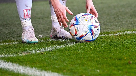 A soccer player puts the ball on the grass