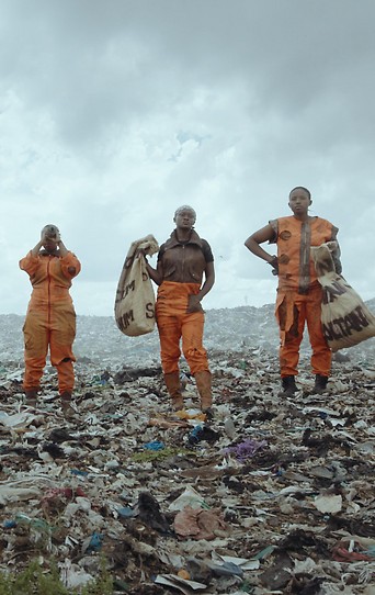 Fünf Personen stehen auf einem gigantischem Müllberg