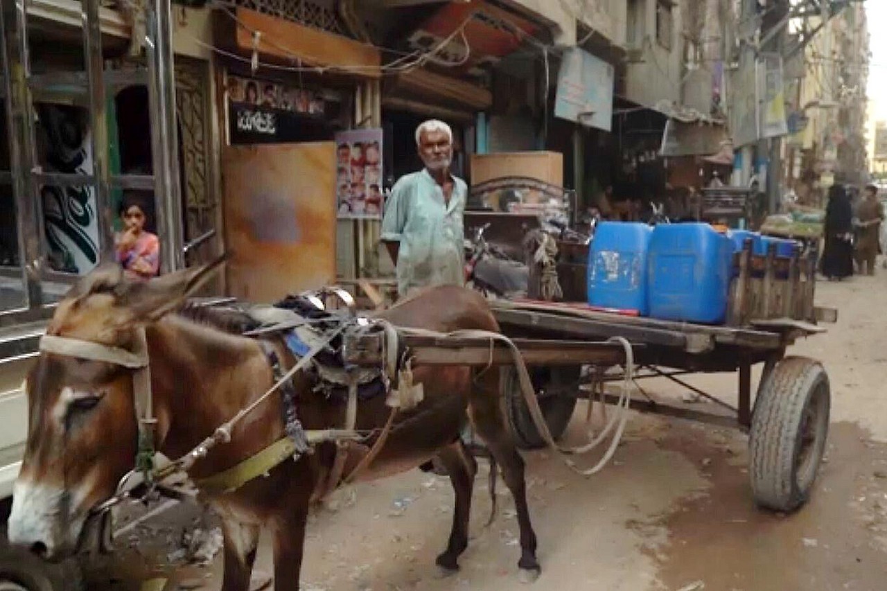 ein Mann steht hinter einem Wagen in einer Gasse in Pakistan 