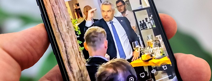 Person sieht sich auf einem Smartphone ein Video mit Bundeskanzler Karl Nehammer (ÖVP) an