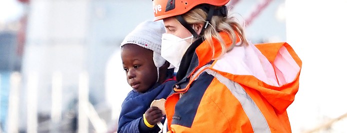Freiwillige des Roten Kreuzes bringt ein Kleinkind von einem Flüchtlingsboot im Hafen von Neapel, Italien