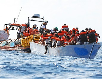 Schlauchboot mit Mitarbeitern einer NGO neben einem Boot mit Migranten