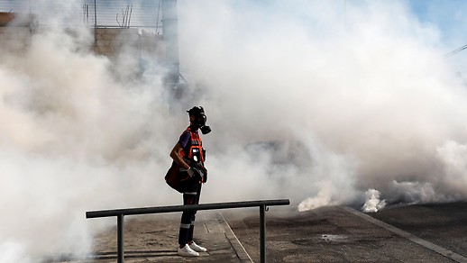 一名巴勒斯坦急救人员在烟雾中戴着防毒面具