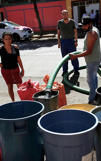 Menschen in Mexiko City stehen bei einem Wassertruck um Wasser zu holen