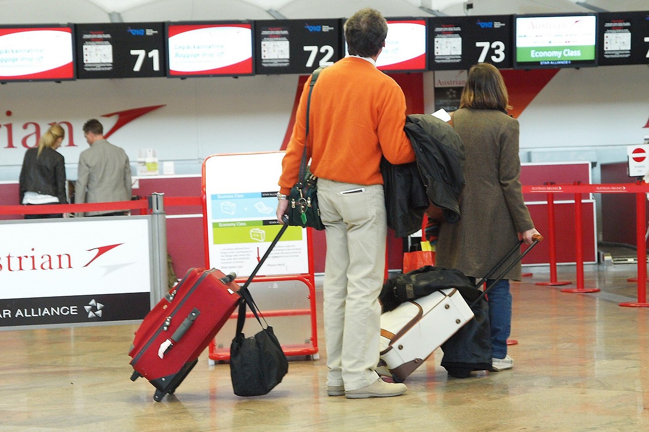 Passengers with luggage in front of the AUA counter at Vienna-Schwechat Airport