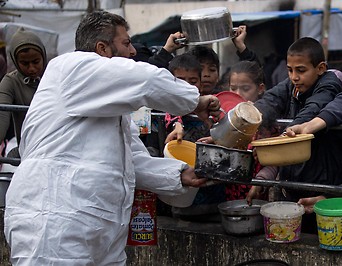 mehrere Kinder beim Abholen von kostenlosen Essensrationen in Rafah 