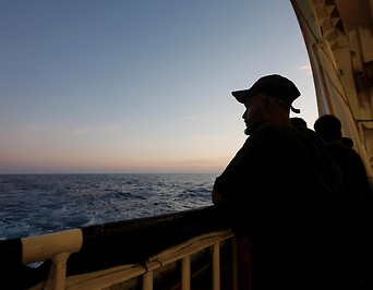 Ein Geflüchteter blickt von einem Rettungsschiff aufs offene Meer