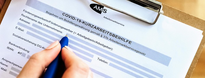 Person füllt ein AMS-Formular zur Covid-19-Kurzarbeitsbeihilfe aus
