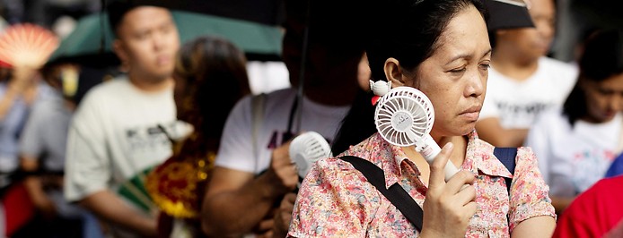 Eine Frau in Manila kühlt ihren Kopf mit einem Mini-Ventilator