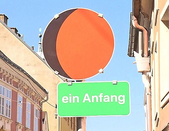 Schild mit orangefarbenen Kreis und ein weiteres Schild mit den Text „ein Anfang“